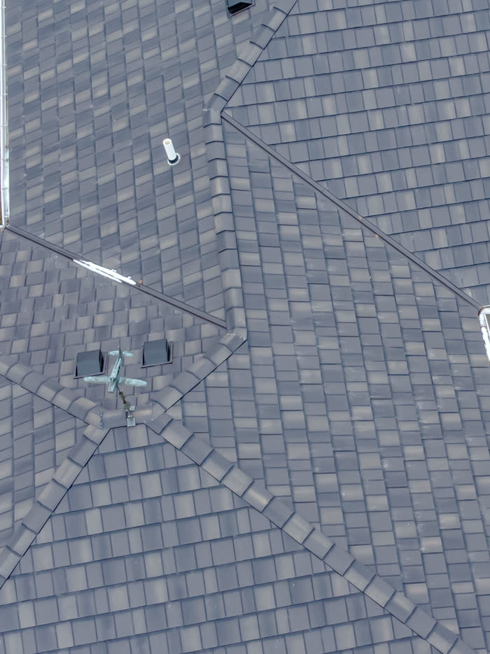 Looking straight down on a hip roof covered in slate gray shingles, its hip lines meeting at the peak